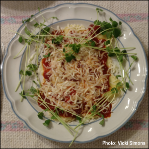 Cheese ravioli topped with marinara sauce and mozzarella cheese -- and surrounded with Speckled Pea microgreens in the shape of a heart.