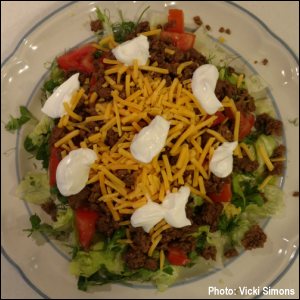 Microgreens mixed with lettuce on a fully prepared taco salad.